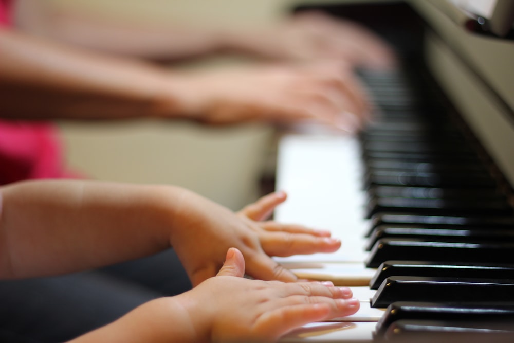 Guru membimbing tangan anak di tuts piano