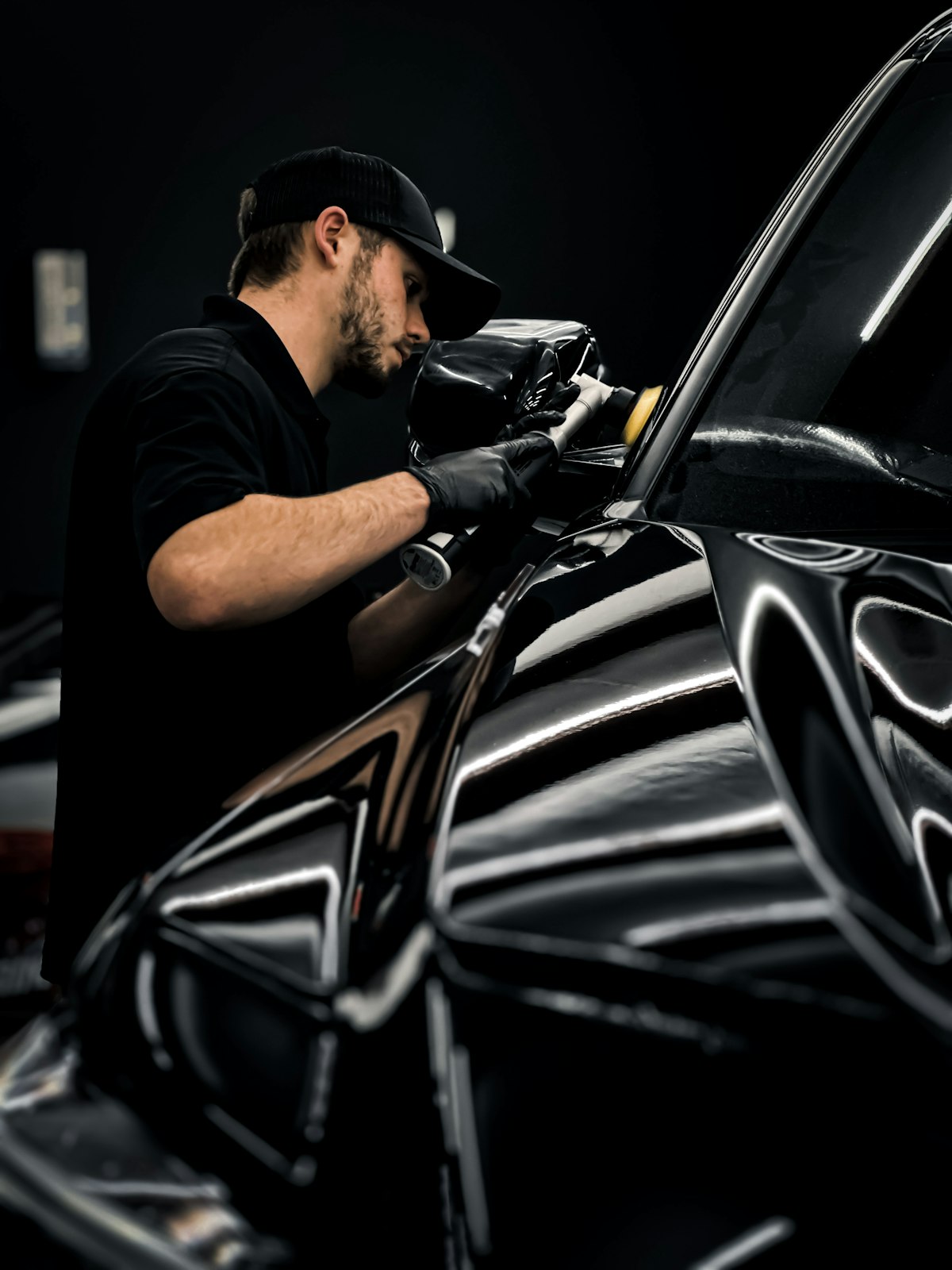 Detailer machine-polishing a black car