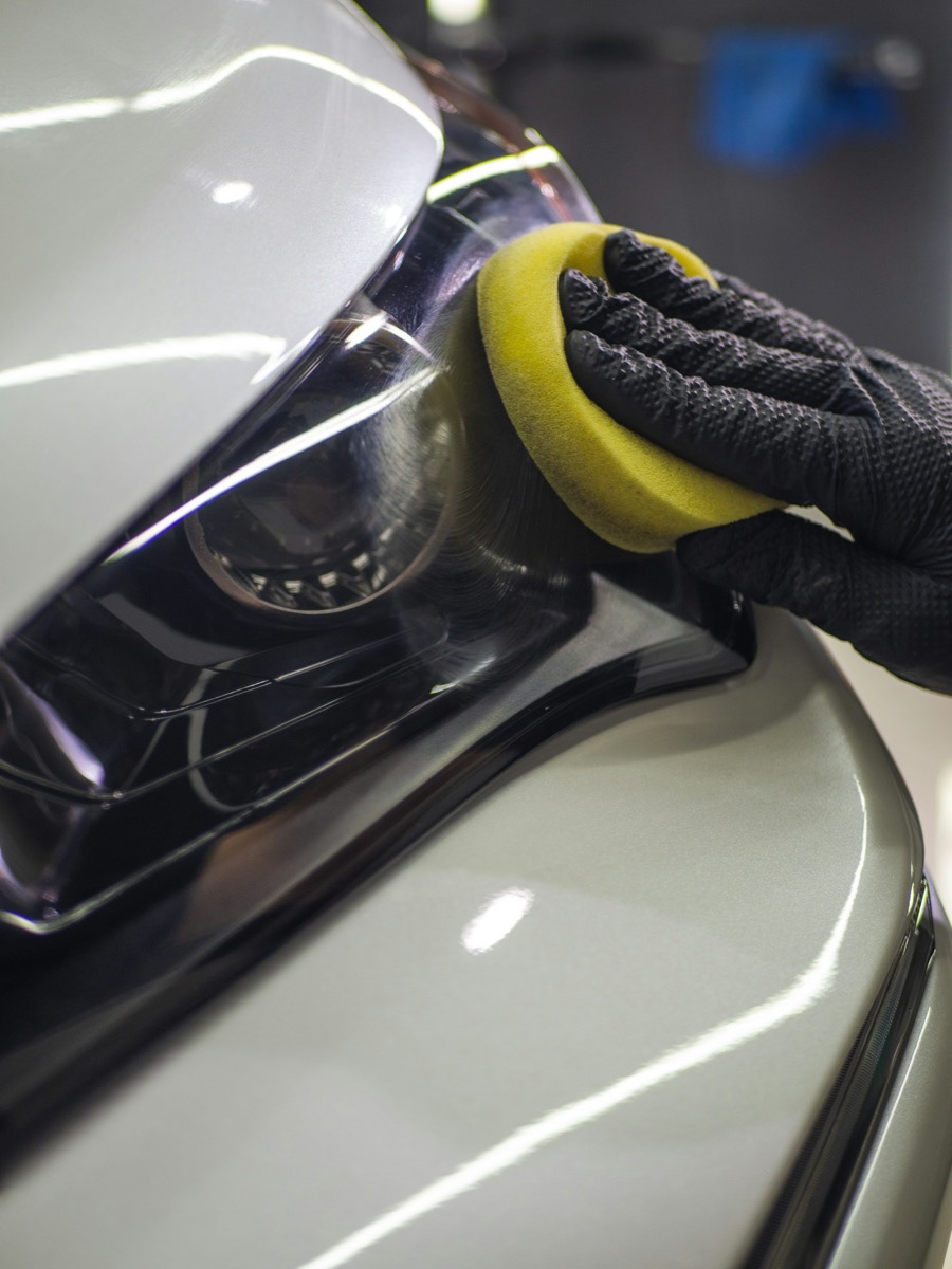 Gloved hand detailing a headlight with an applicator pad